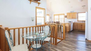 Una cocina amplia con armarios de madera y un comedor con una mesa de vidrio y sillas de mimbre.