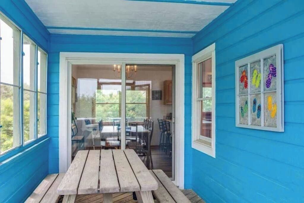 A room with a wooden bench, a glass door leading to a dining area, and a wall with colorful artwork.