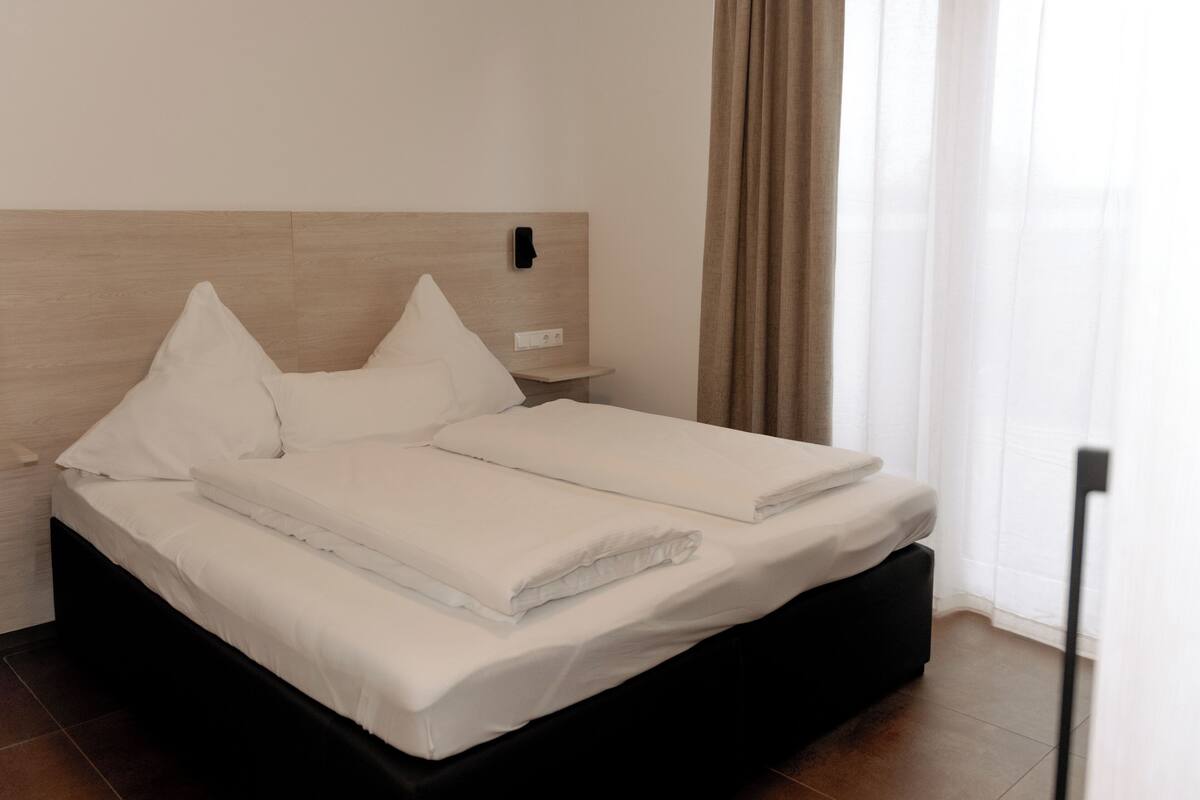 A neatly made bed with white linens in a modern hotel room.