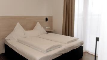 Una cama bien tendida con sábanas blancas en una habitación de hotel moderna.