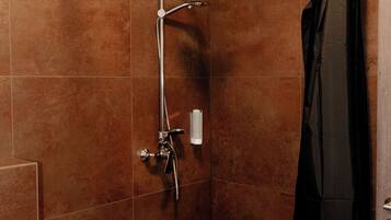 Un espace douche équipé d’un pommeau de douche à main, d’un robinet mural et d’un porte-serviettes.