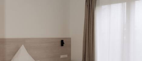 A neatly made bed with white linens in a hotel room.