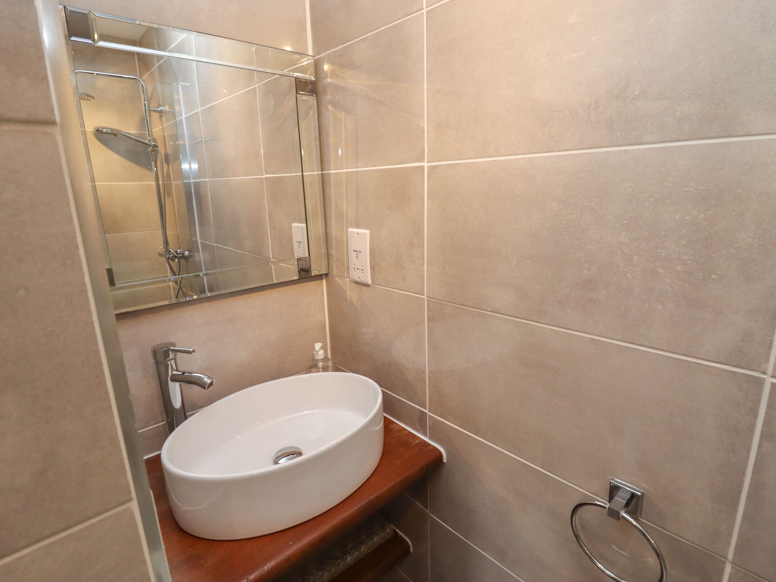 Un baño con lavamanos blanco, espejo y ducha.
