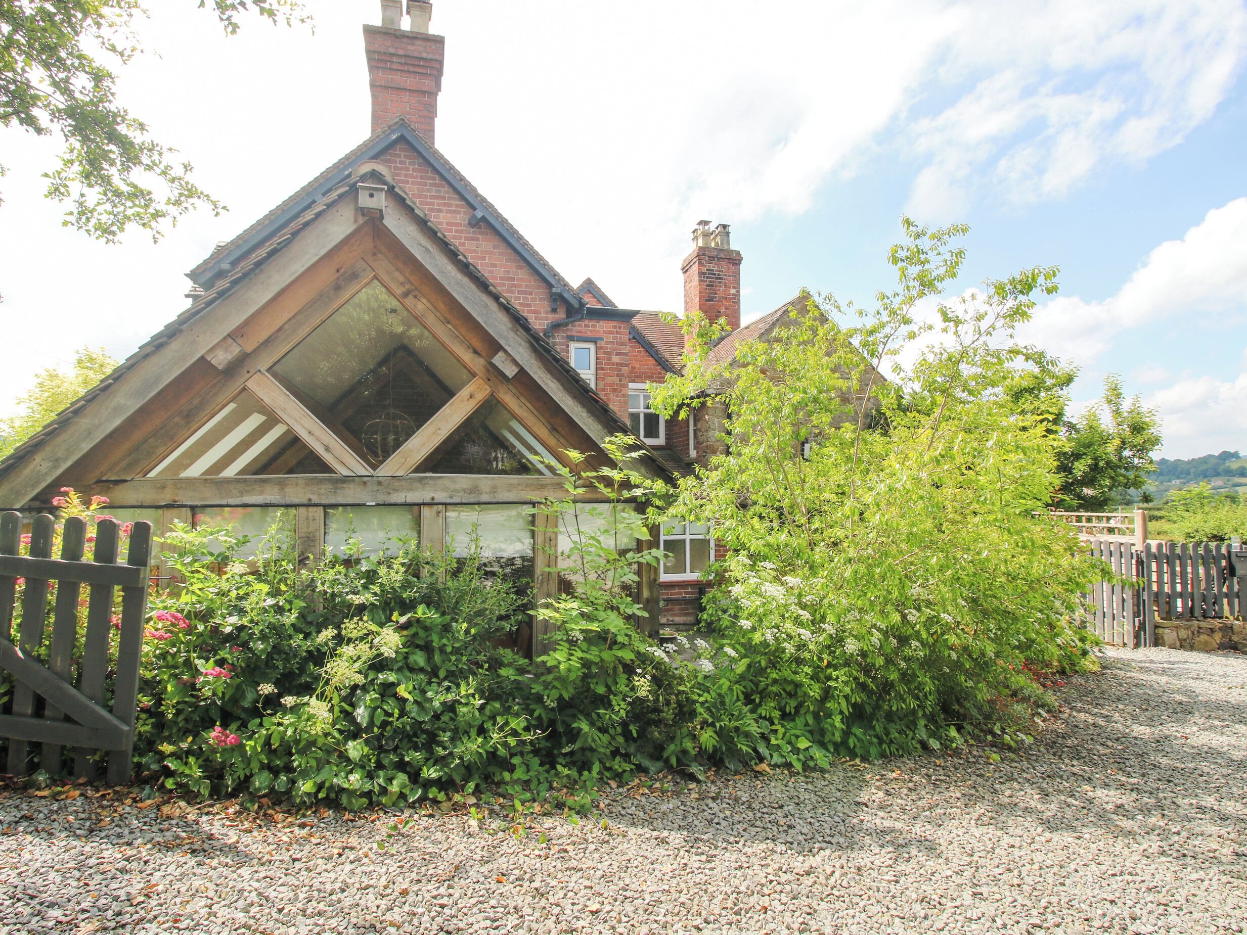 A traditional house with a sloped roof, a visible chimney, and a garden area with gravel and plants.