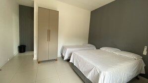 Un dormitorio con dos camas individuales, un armario y una pared gris.