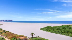 Una playa con vistas despejadas al océano y un horizonte urbano lejano.
