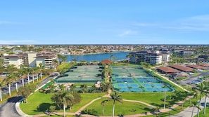 Um resort com várias quadras de tênis, uma piscina e vista para a paisagem urbana ao redor.