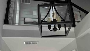 A modern interior with a geometric black chandelier, white walls, and a visible staircase leading to an upper level. - Perfect for Golfer's, P-baller's and Beach Goer's! (Hilton Head Island)