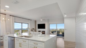 A modern kitchen with white cabinetry, a large island, and a dining area with a view.
