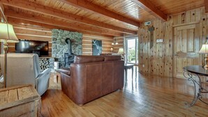 A spacious living room with a stone fireplace, leather sofa, and wooden floors. - Charmante, spacieuse maison canadienne/Charming and very spacious Canadian house (Saint-Jérôme)
