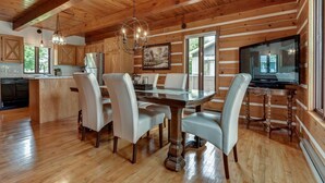 A wooden cabin interior with a dining area, kitchen, and a large TV. - Charmante, spacieuse maison canadienne/Charming and very spacious Canadian house (Saint-Jérôme)
