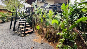 A building with a staircase leading to a covered area, surrounded by lush greenery and a gravel path. - Casa Cariad *Cottage house near Playa Bejuco*

 (Provincia de Puntarenas)