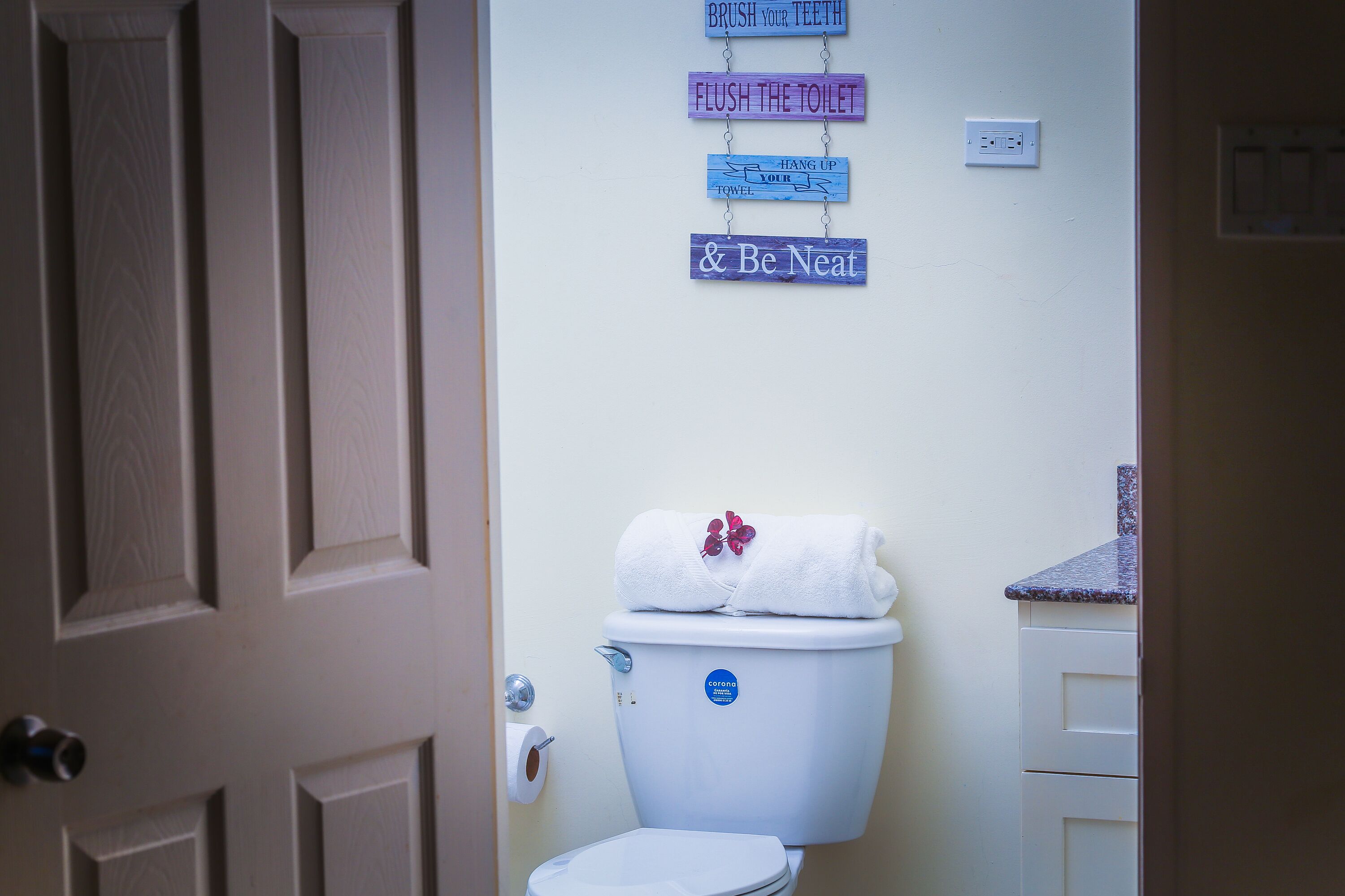 A bathroom with a toilet, a towel on the tank, and a wall-mounted sign with instructions.