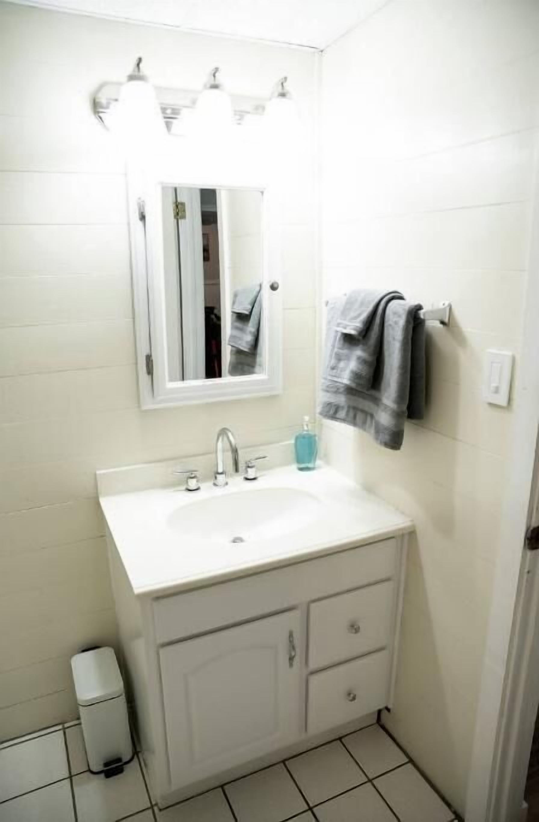 A small bathroom with a white sink, a mirror, and a towel rack.
