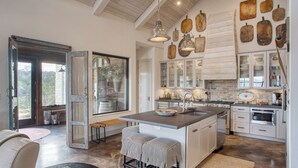 Une cuisine spacieuse dotée d’un grand îlot central, de touches de bois et offrant une vue sur l’extérieur.