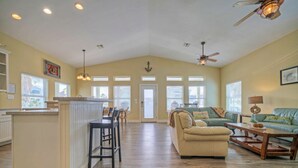 A spacious living area with a high ceiling, a kitchen island, and a seating area with a sofa and coffee table. - Jones N by the Beach by Avantstay Walk to Beach (Port Aransas)