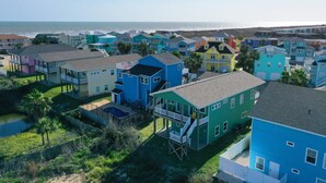 A coastal residential area with colorful houses, a beach, and a clear view of the ocean. - Jones N by the Beach by Avantstay Walk to Beach (Port Aransas)