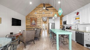 Une cuisine moderne avec des meubles blancs, un réfrigérateur en acier inoxydable et une table à manger de couleur turquoise.