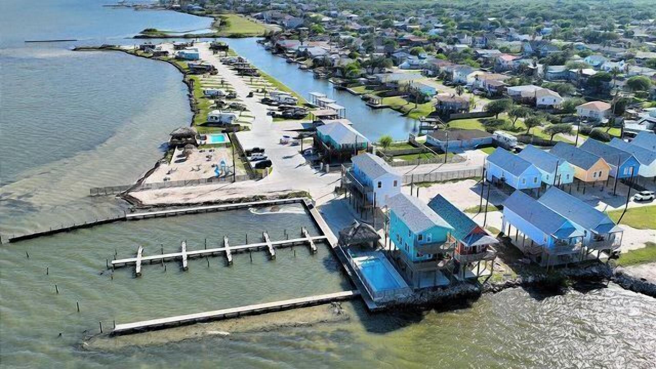 An aerial view of a coastal residential area with houses, a dock, and a marina.