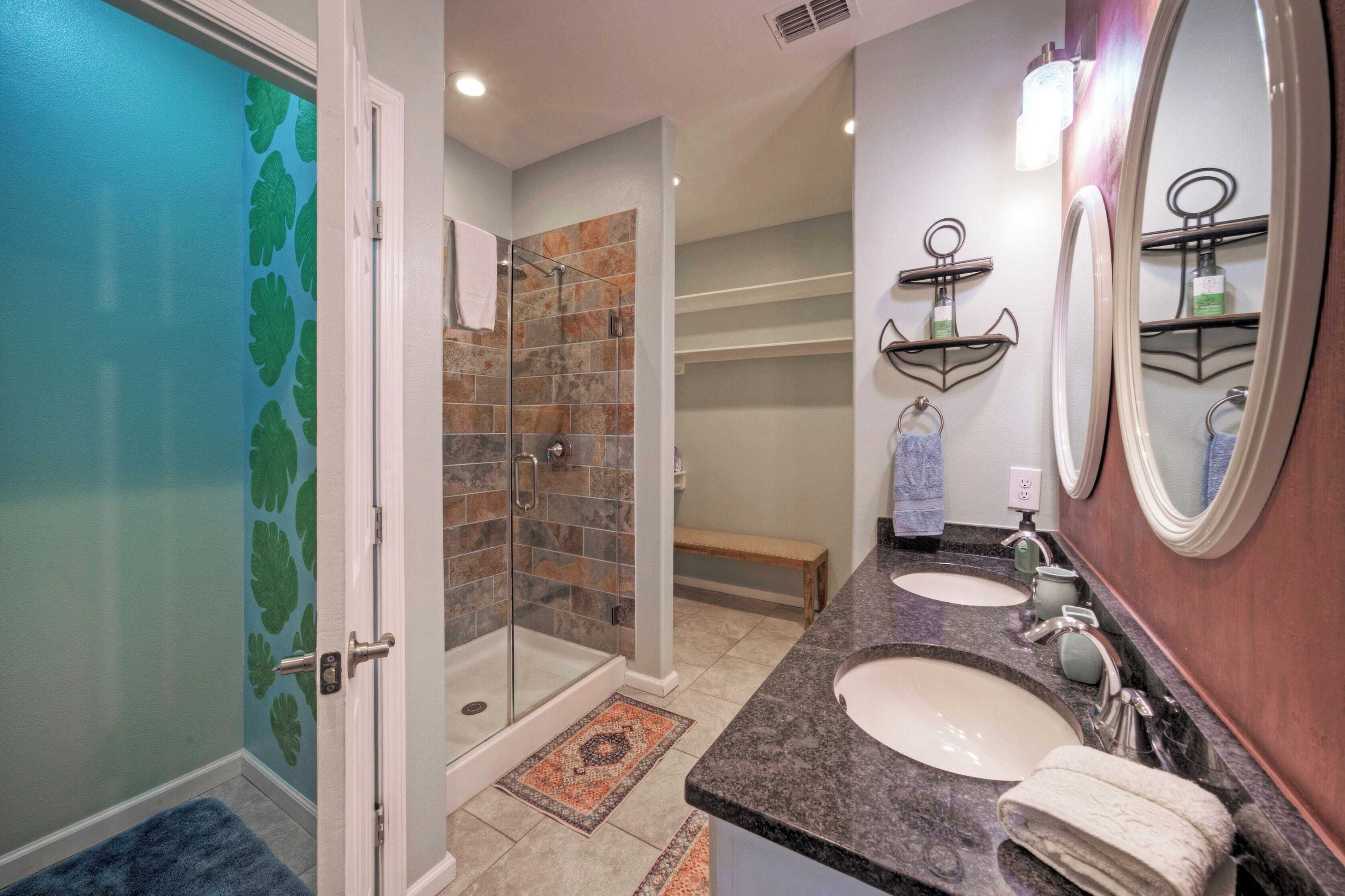 A bathroom with a glass shower, two sinks, and a large mirror.