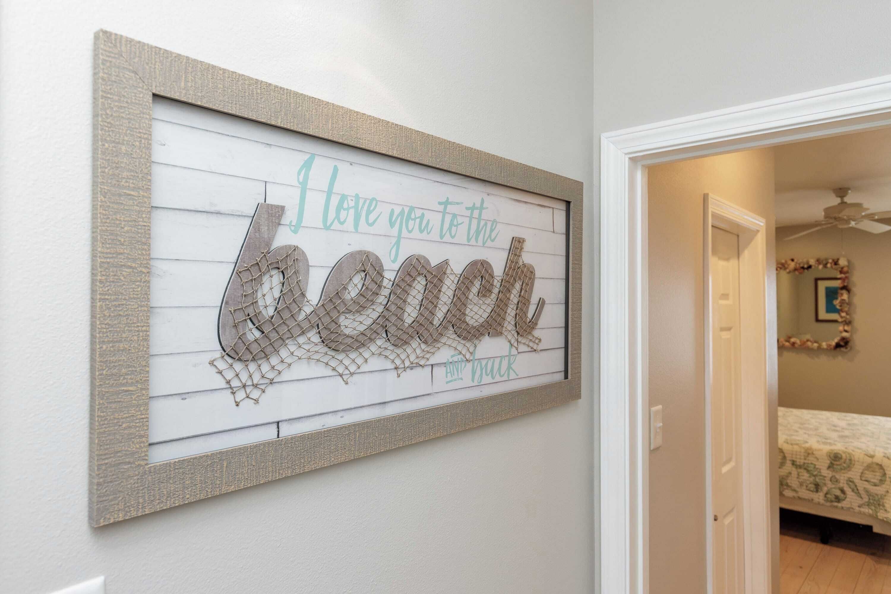 A framed artwork with the text "I love you to the beach" on a white background.