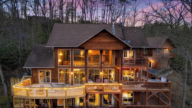 Une cabane en bois à plusieurs étages, dotée de nombreuses terrasses et de grandes fenêtres, et entourée d’arbres.