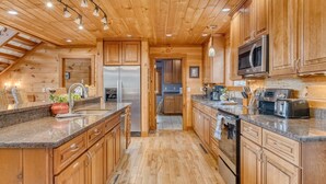 Une cuisine moderne dotée de meubles en bois, d’appareils électroménagers en acier inoxydable et d’un plan de travail en granit.