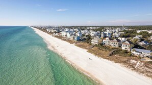 An aerial view of a coastal town with a long sandy beach and white houses.