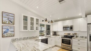 Een moderne keuken met witte kasten, roestvrijstalen apparatuur en een marmeren aanrecht.