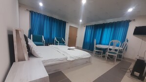 Una habitación de hotel con cama, escritorio, dos sillas y televisor.