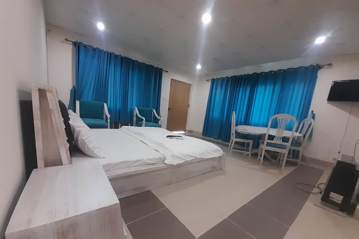 A hotel room with a bed, a desk, two chairs, and a TV.