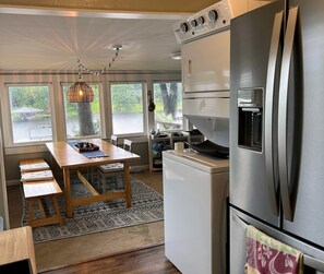 A modern kitchen with a stainless steel refrigerator, a built-in oven, and a dining area with a wooden table and benches. - Waterfront cottage with private two-story boat dock (Eatonton)