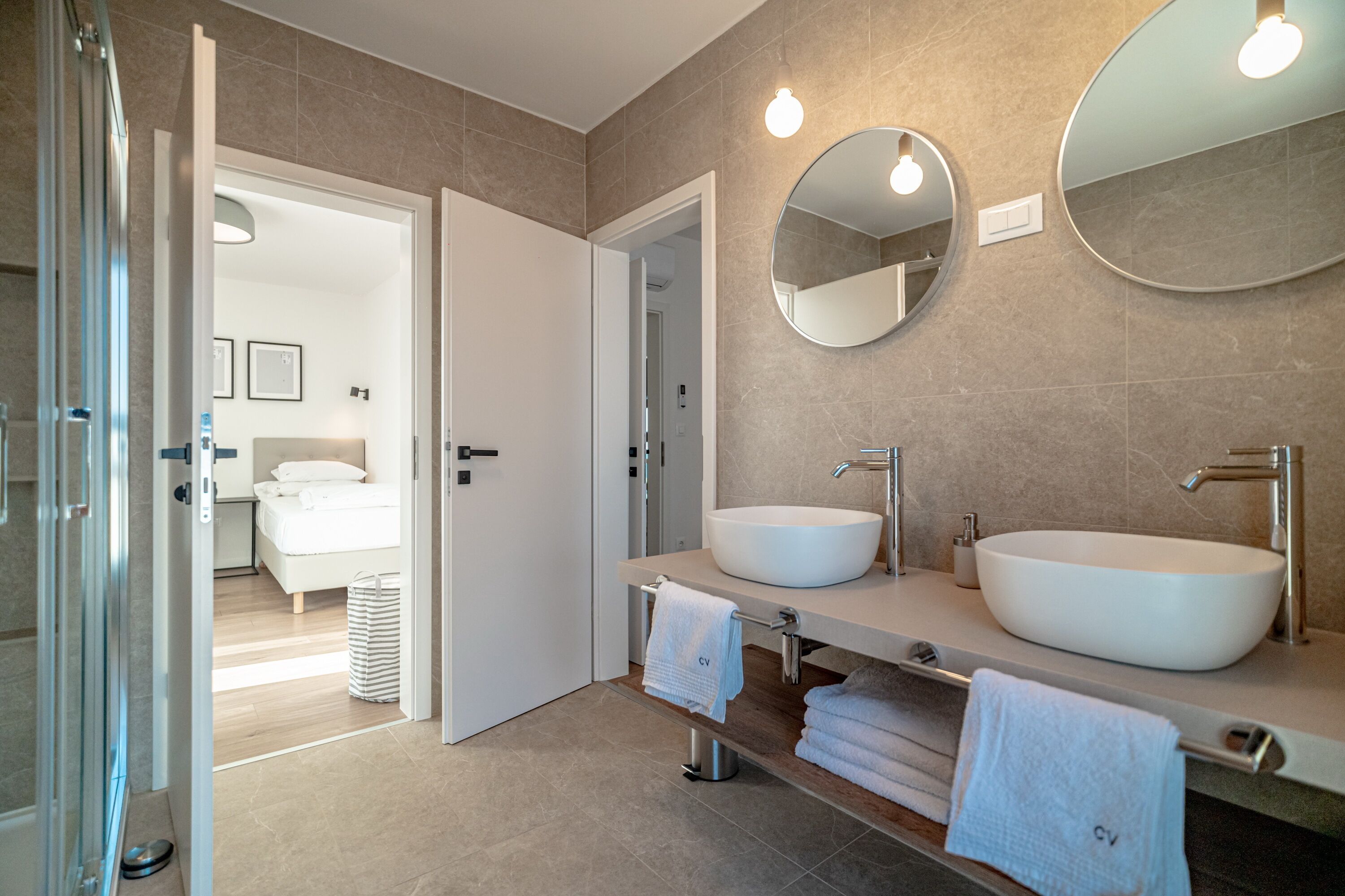 A modern bathroom with two large sinks, a mirror, and a shower area.