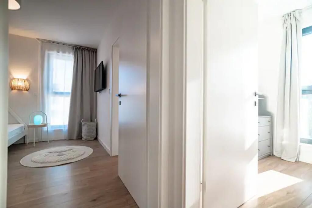 A room with a bed, a chair, a TV, and a window with curtains.