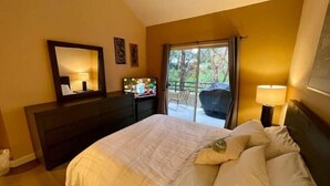 A hotel room with a bed, a dresser, a mirror, a desk, and a view of the outdoors. - Beautiful Laguna 2 Bedroom Condo (Laguna Niguel)