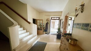 Un pasillo espacioso con una escalera blanca, un banco de madera y un espejo fijado a la pared.