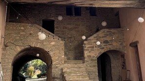 Un edificio de piedra con una entrada arqueada y una escalera que lleva a un segundo nivel.