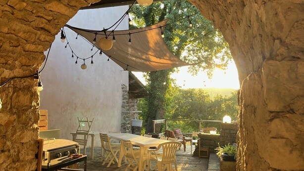 Un espacio de comedor al aire libre con paredes de piedra, una mesa de madera y sillas.