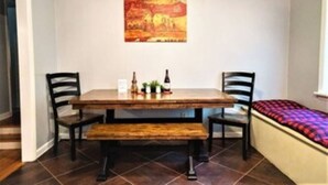 A dining area with a wooden table, two chairs, a bench, and a painting on the wall. - Edward's Place ~ Family Retreat Near Downtown & Oaklawn (Hot Springs)