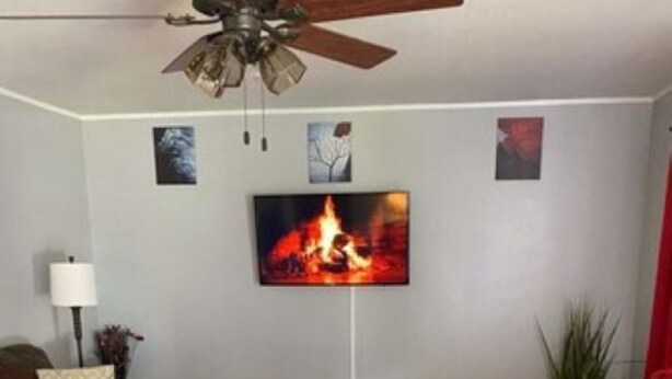 A living room with a ceiling fan, a fireplace with a TV above it, two leather sofas, and a coffee table. - Edward's Place ~ Family Retreat Near Downtown & Oaklawn (Hot Springs)
