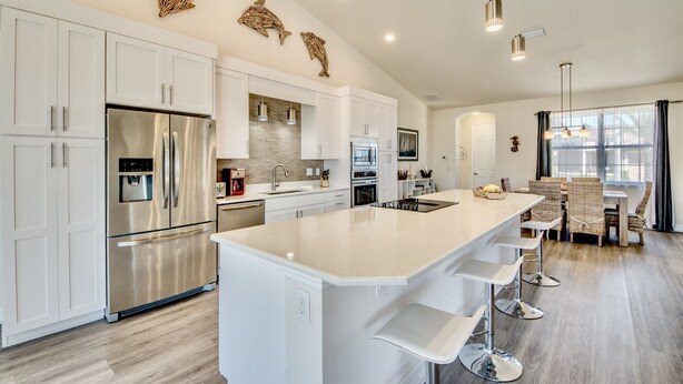 A modern kitchen with white cabinetry, stainless steel appliances, and a large island with bar stools. - Special Offer Villa Felicity - river access, pool & spa, quiet, charming (Cape Coral)
