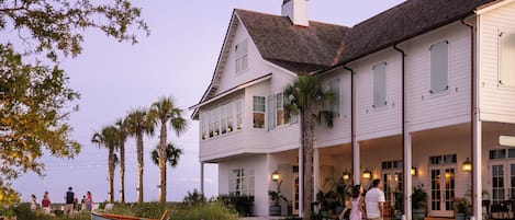 A two-story building with a covered porch and a boat in the foreground.