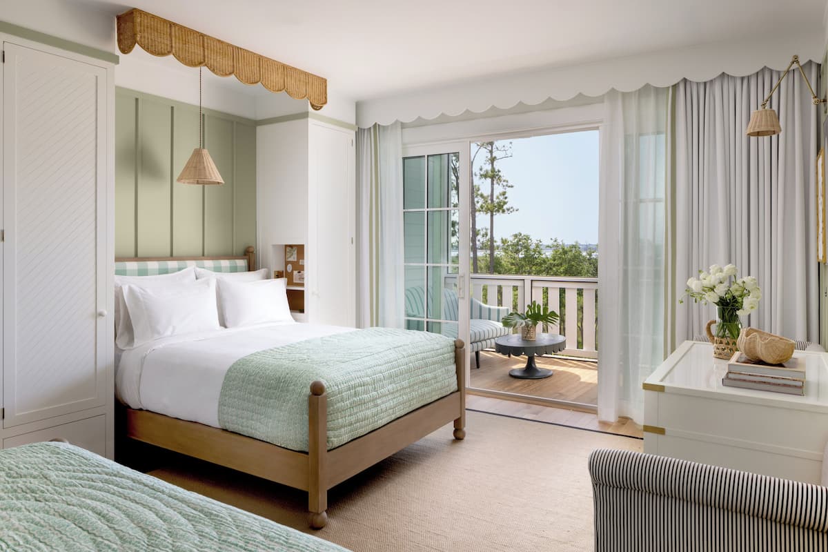 A bedroom with a bed, a nightstand, a chair, and a view of the balcony.