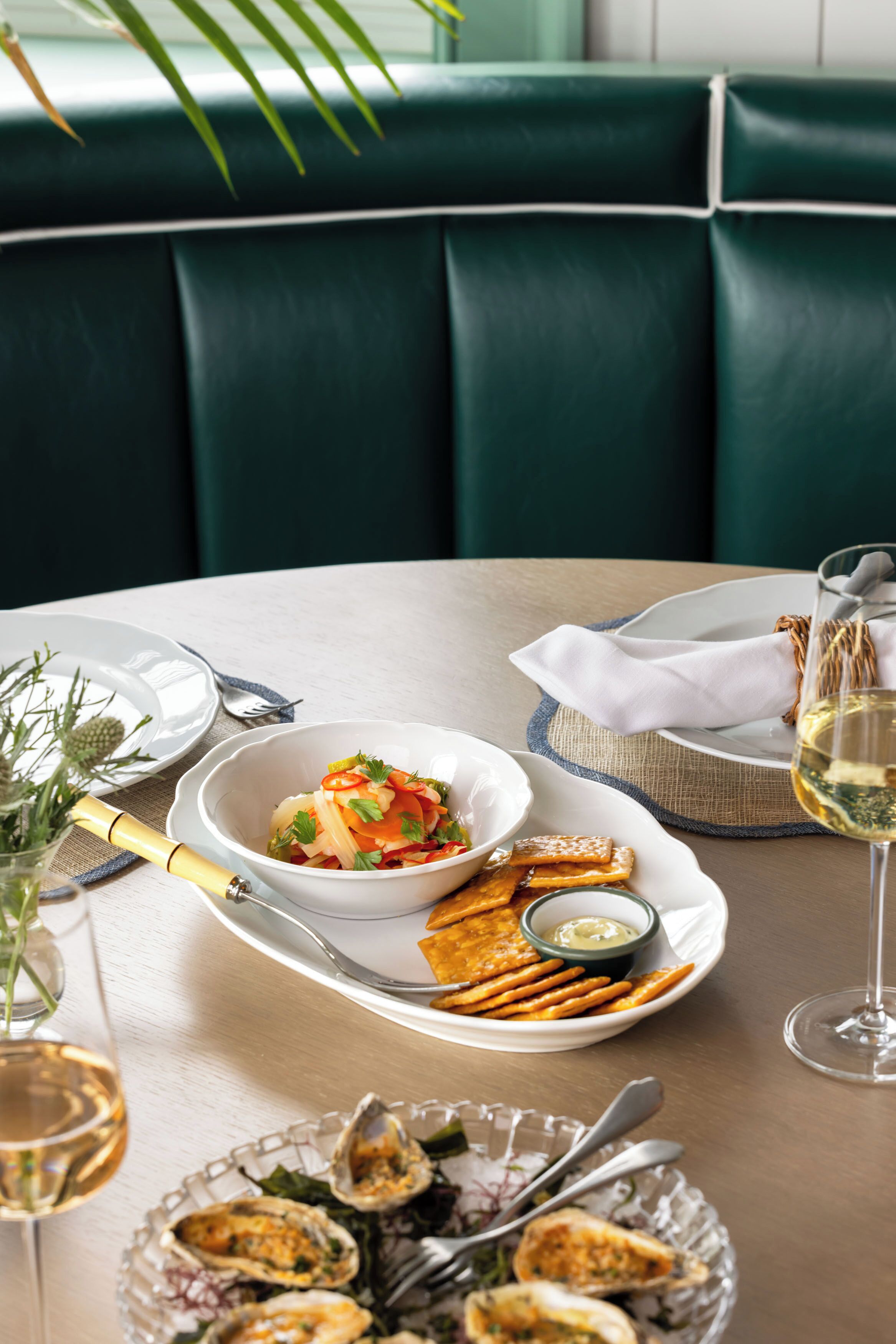 Una mesa de comedor con un bol de ensalada, un plato de palitos de pretzel y una copa de vino.