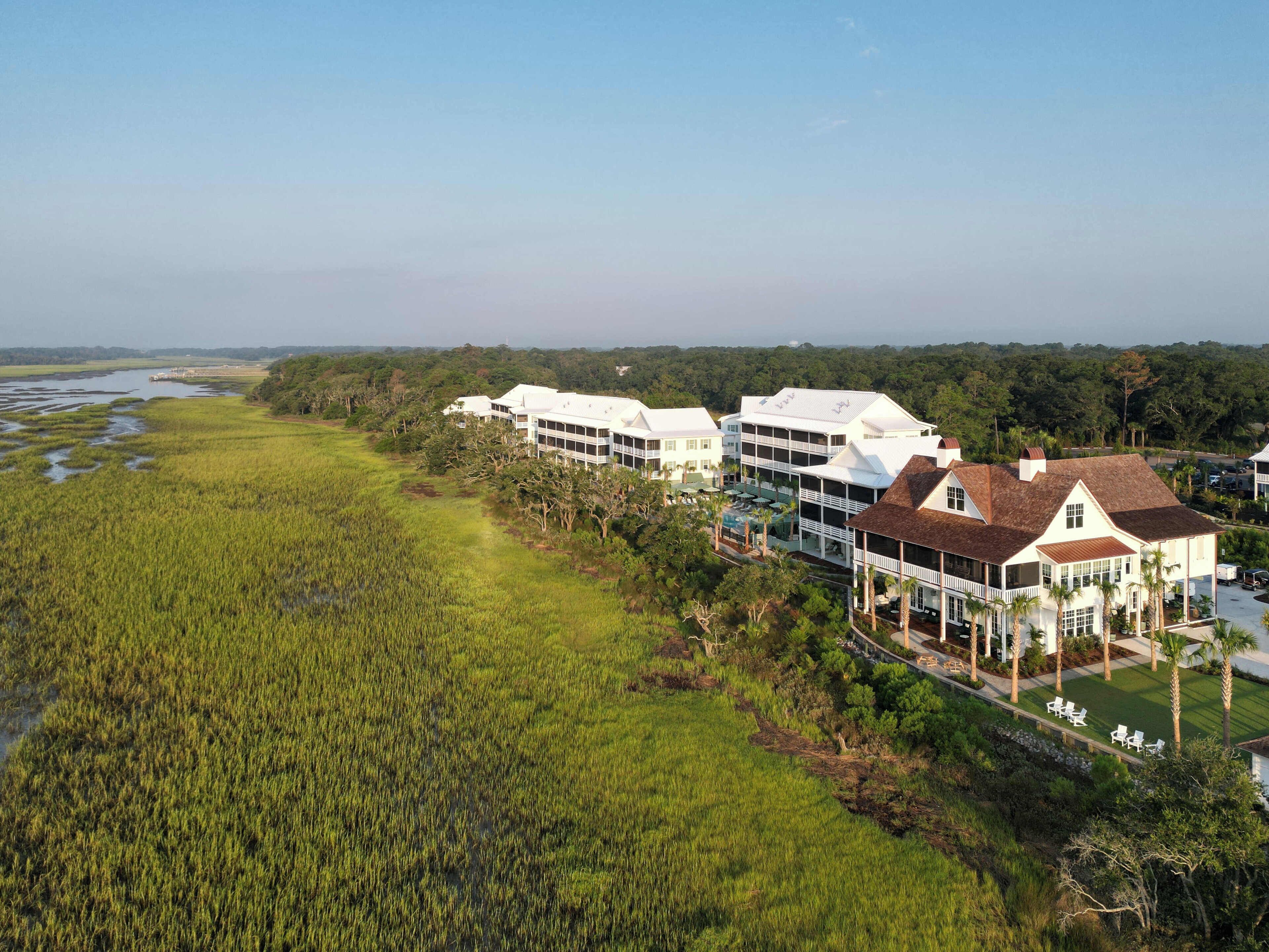 A coastal hotel with multiple white buildings, a grassy area, and a view of the sea.