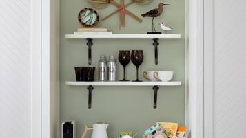 A kitchen with white cabinetry, a leaf decoration, and shelves with kitchenware.