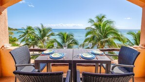 A dining table with plates and cutlery, overlooking a beach with palm trees and the ocean. - Relax in Your Private Beachfront Retreat, Surrounded by Breathtaking Ocean Views (Akumal)