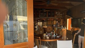 A kitchen with wooden cabinets, a dining area with a round table and chairs, and a large window with decorative glass. - Living Life Dockside (Naval Air Station Key West)