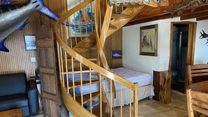 A spiral staircase with a wooden finish, a bed with white bedding, a black leather sofa, and a wooden chair. - Living Life Dockside (Naval Air Station Key West)