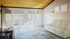 Ein Zimmer mit einem weißen Sofa, einem Deckenventilator und einem großen Fenster.